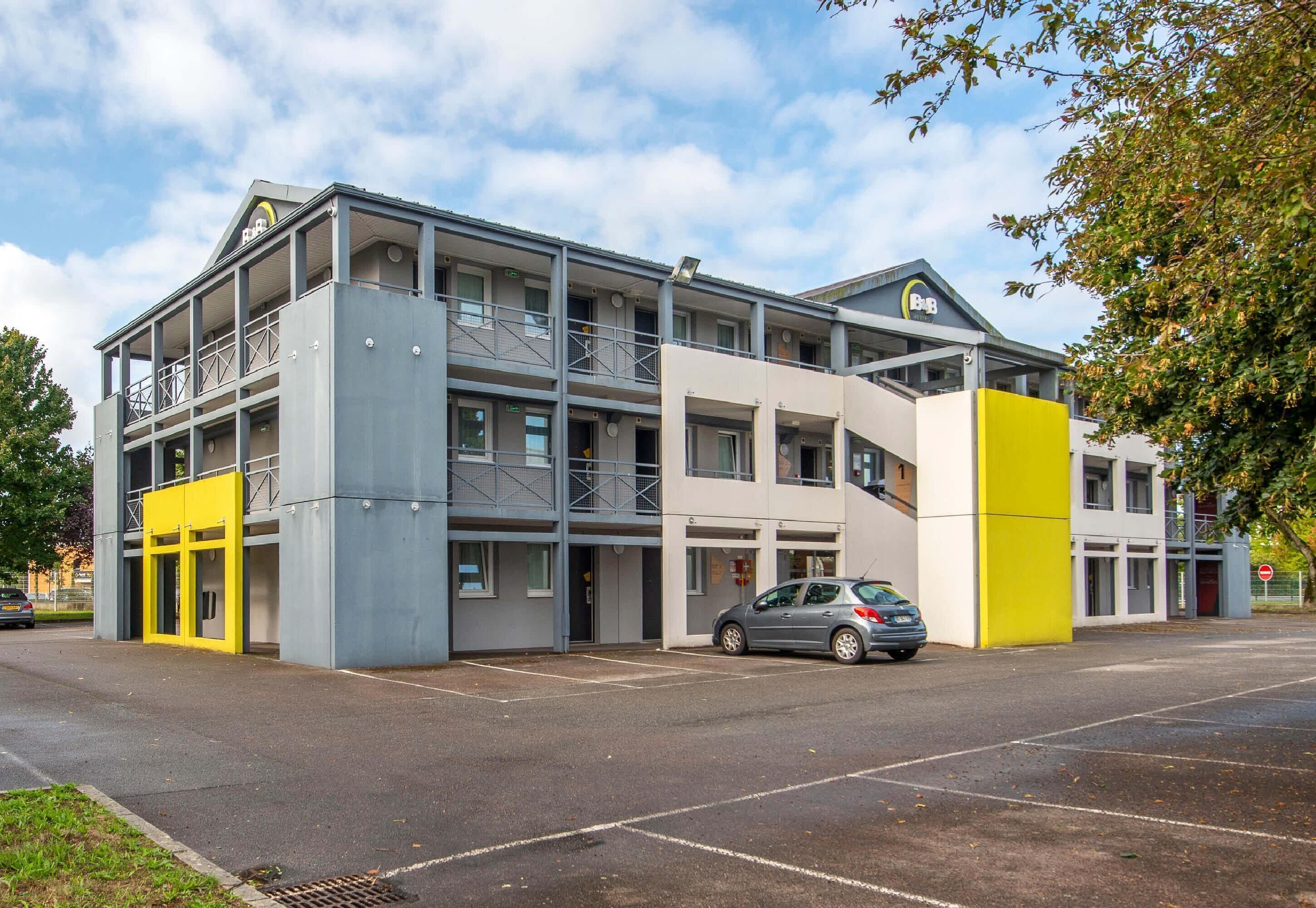 A multi-story building with a parking lot and a car parked in front.