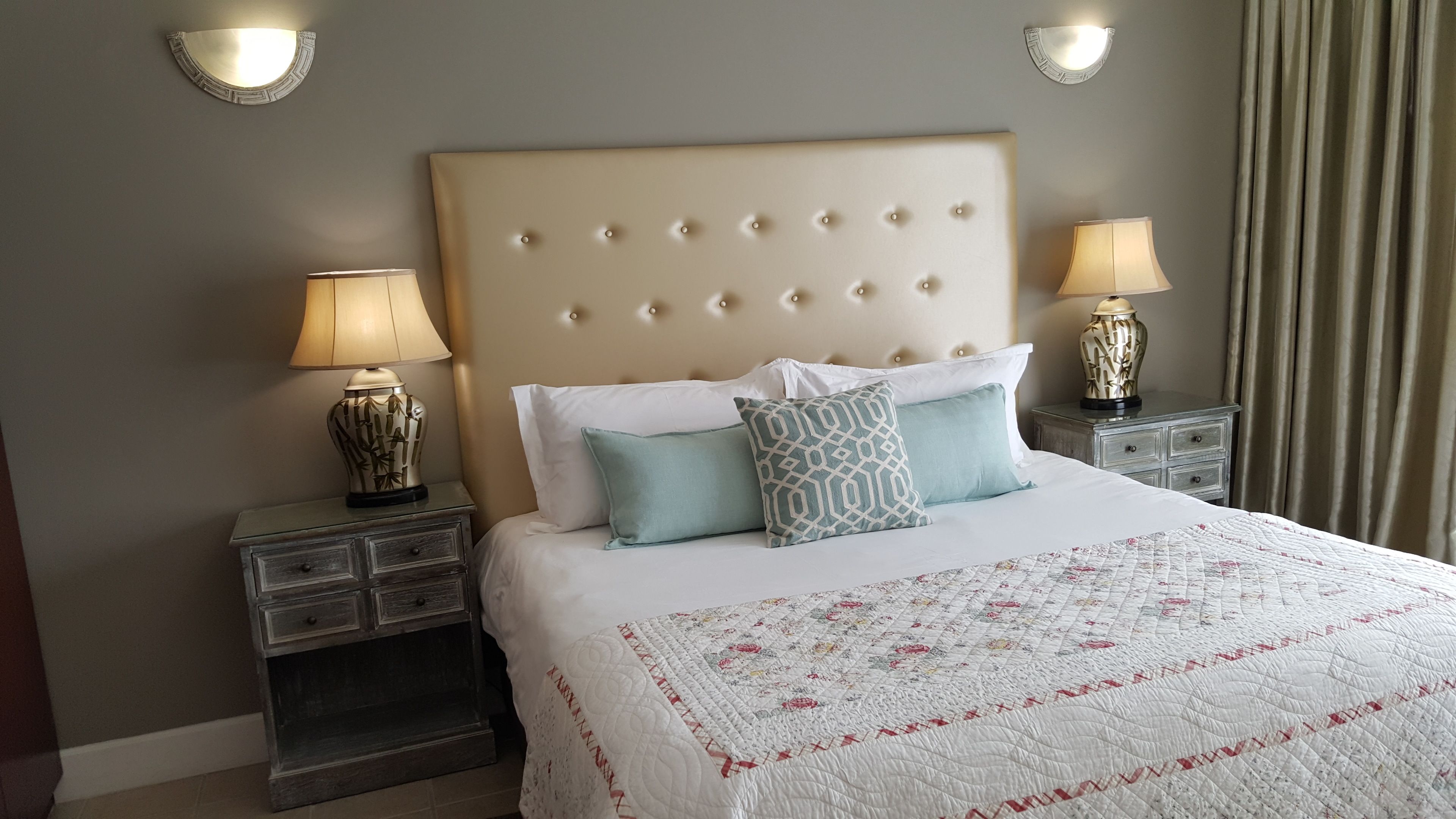 A hotel room with a large bed, two bedside tables with lamps, and a headboard with a tufted design.