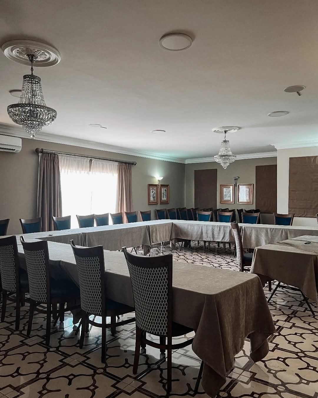 A conference room with a long table, chairs, and chandeliers.