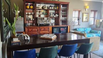 Une cuisine dotée d’un îlot central, de tabourets de bar, d’une machine à café et d’une bibliothèque remplie de divers objets.