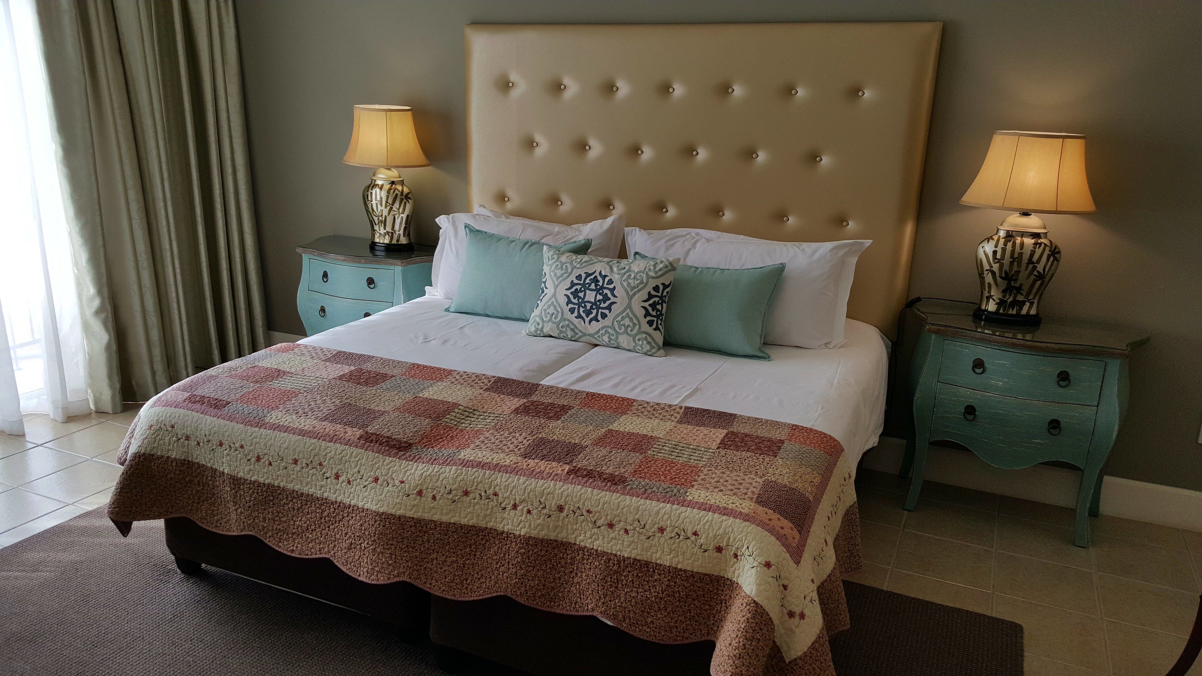 A neatly made bed with a quilt, two bedside tables with lamps, and a headboard.