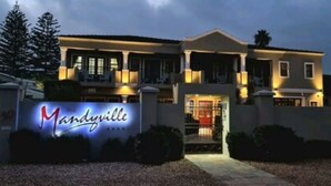 A large, two-story house with a prominent sign reading "Manlyville." - The Mandyville (Jeffreys Bay)