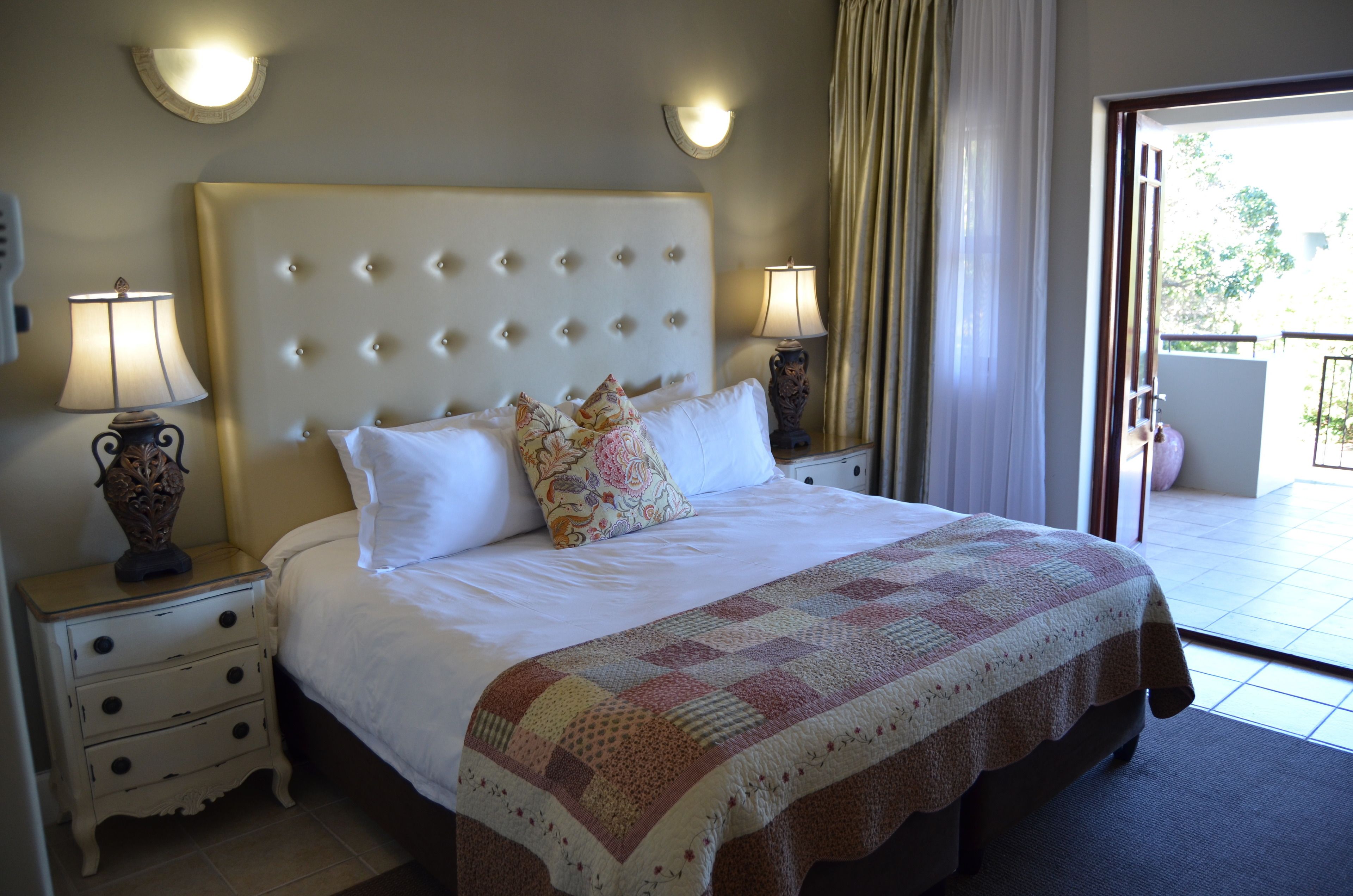 Een hotelkamer met een groot bed, twee bedlampen, een decoratieve vaas en uitzicht op het omliggende landschap.