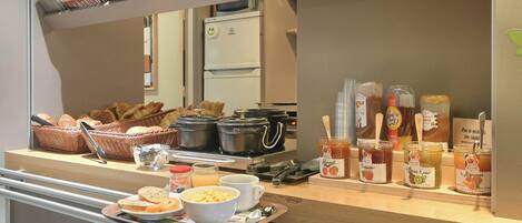 A breakfast bar with bread, pastries, and condiments.