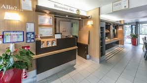 A reception desk with a sign reading "Bienvenue chez BB" and a "Welcome home" sign above it. - B&B HOTEL Toulouse Cité de l'Espace Mouchotte (Toulouse)