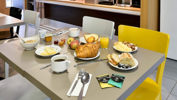 A breakfast table with croissants, eggs, bacon, and juice. - B&B HOTEL Toulouse Cité de l'Espace Mouchotte (Toulouse)