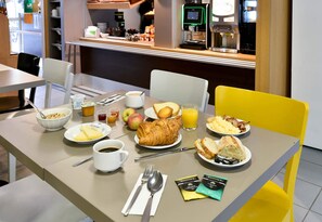 A breakfast table with croissants, eggs, bacon, and juice. - B&B HOTEL Toulouse Cité de l'Espace Mouchotte (Toulouse)