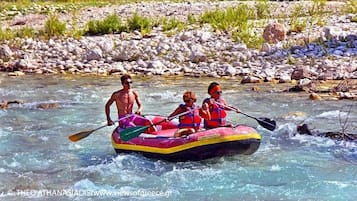 Un gruppo di persone fa rafting su un fiume circondato da rocce e vegetazione.