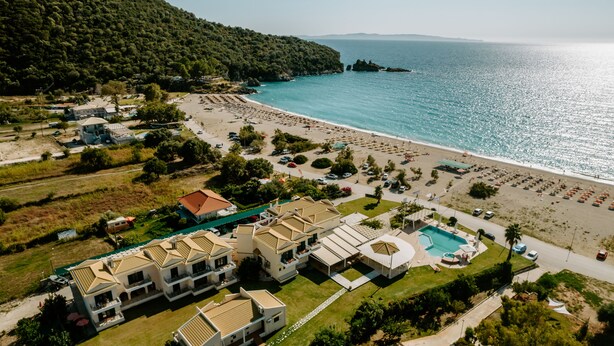 Vista aérea de un complejo turístico costero con varios edificios, una playa y una piscina.