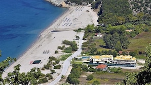 Vista aérea de una zona costera con playa, carretera y varios edificios con tejados amarillos.