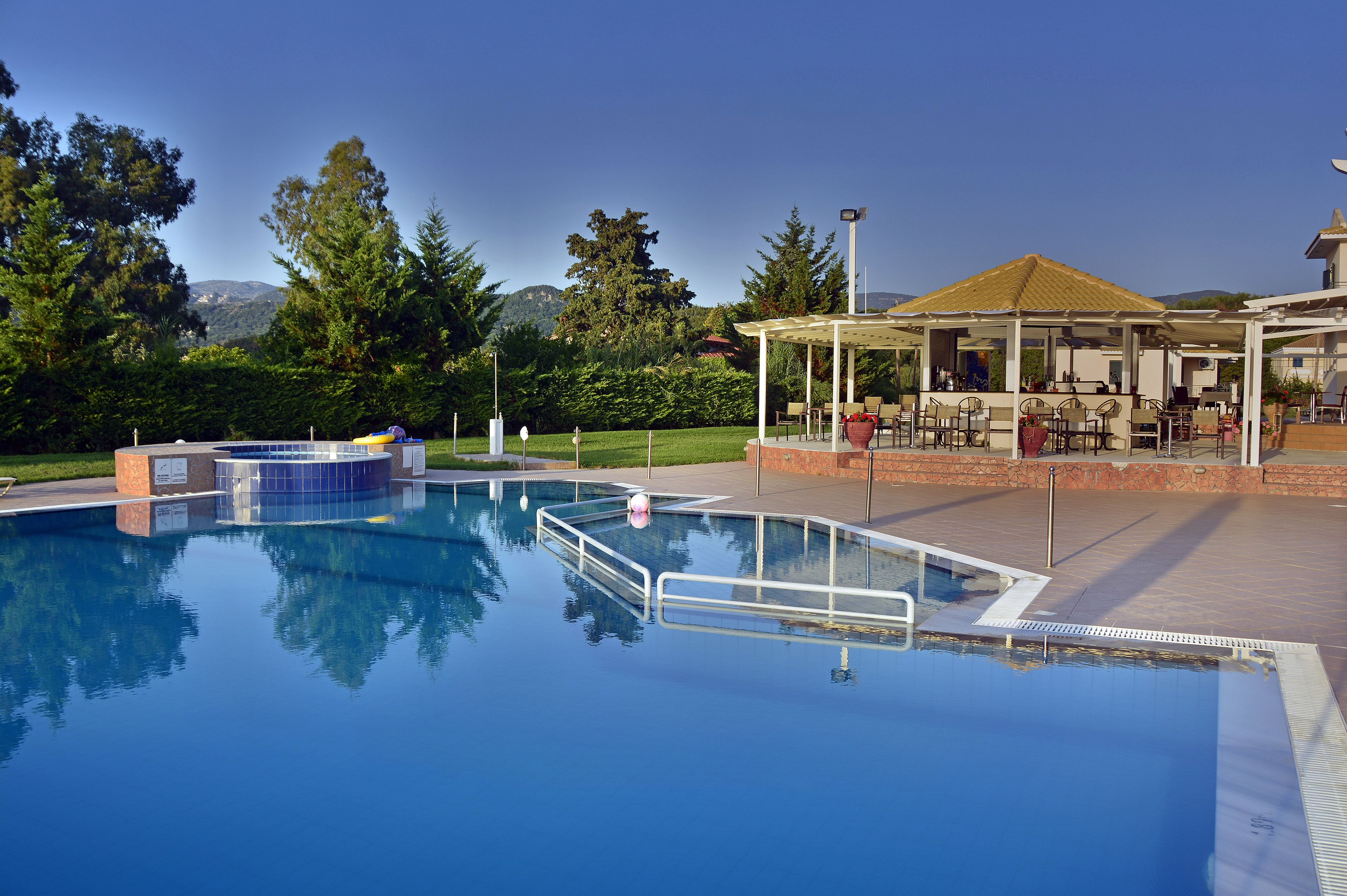 A swimming pool with a sunken hot tub, surrounded by a covered patio area with outdoor seating.