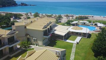 A coastal hotel with multiple buildings, a swimming pool, and a beach area.