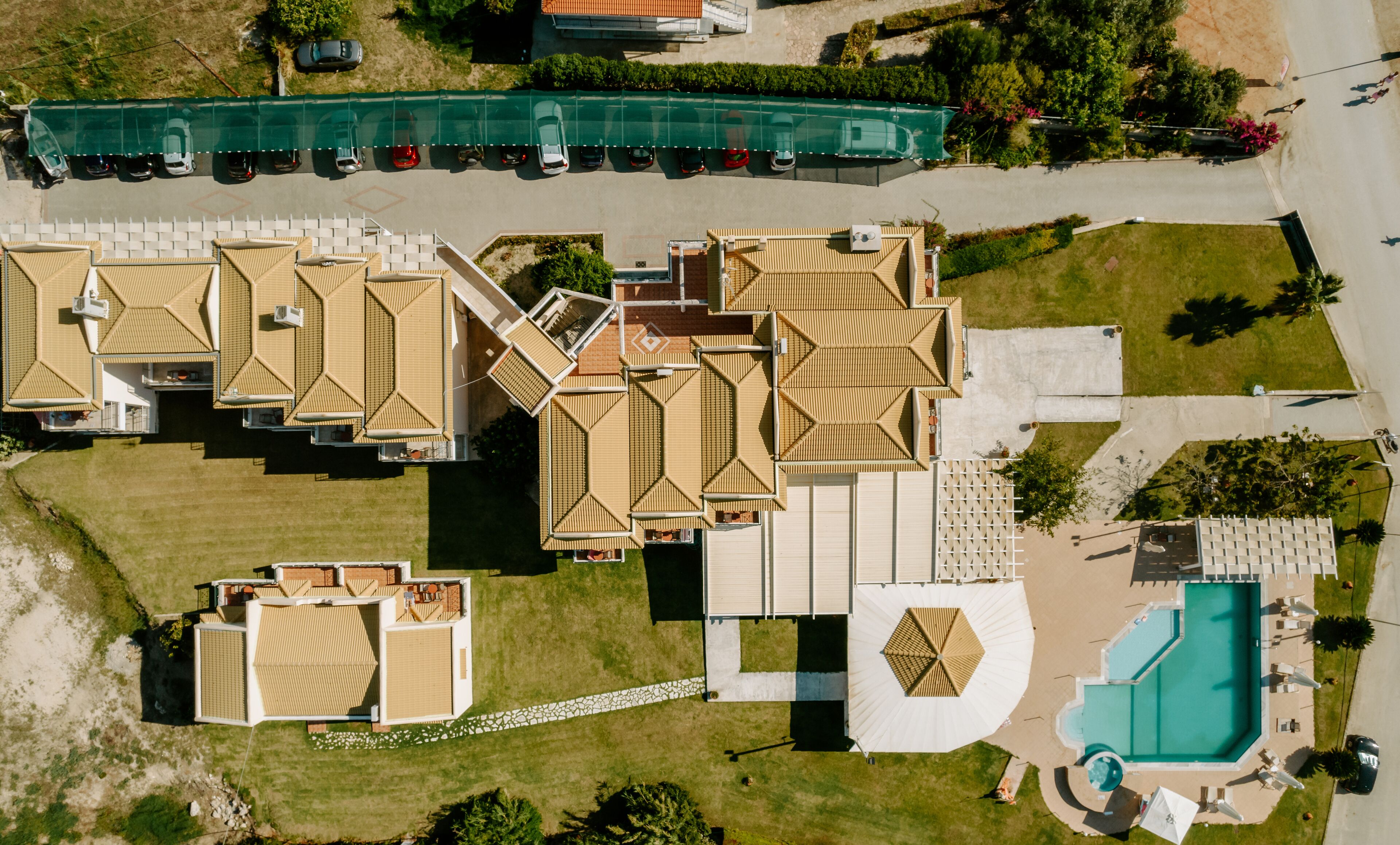 Vista aérea de un hotel con varias construcciones, una piscina y un estacionamiento.