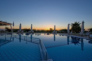 Una piscina al aire libre, sombrillas, sillones reclinables de piscina