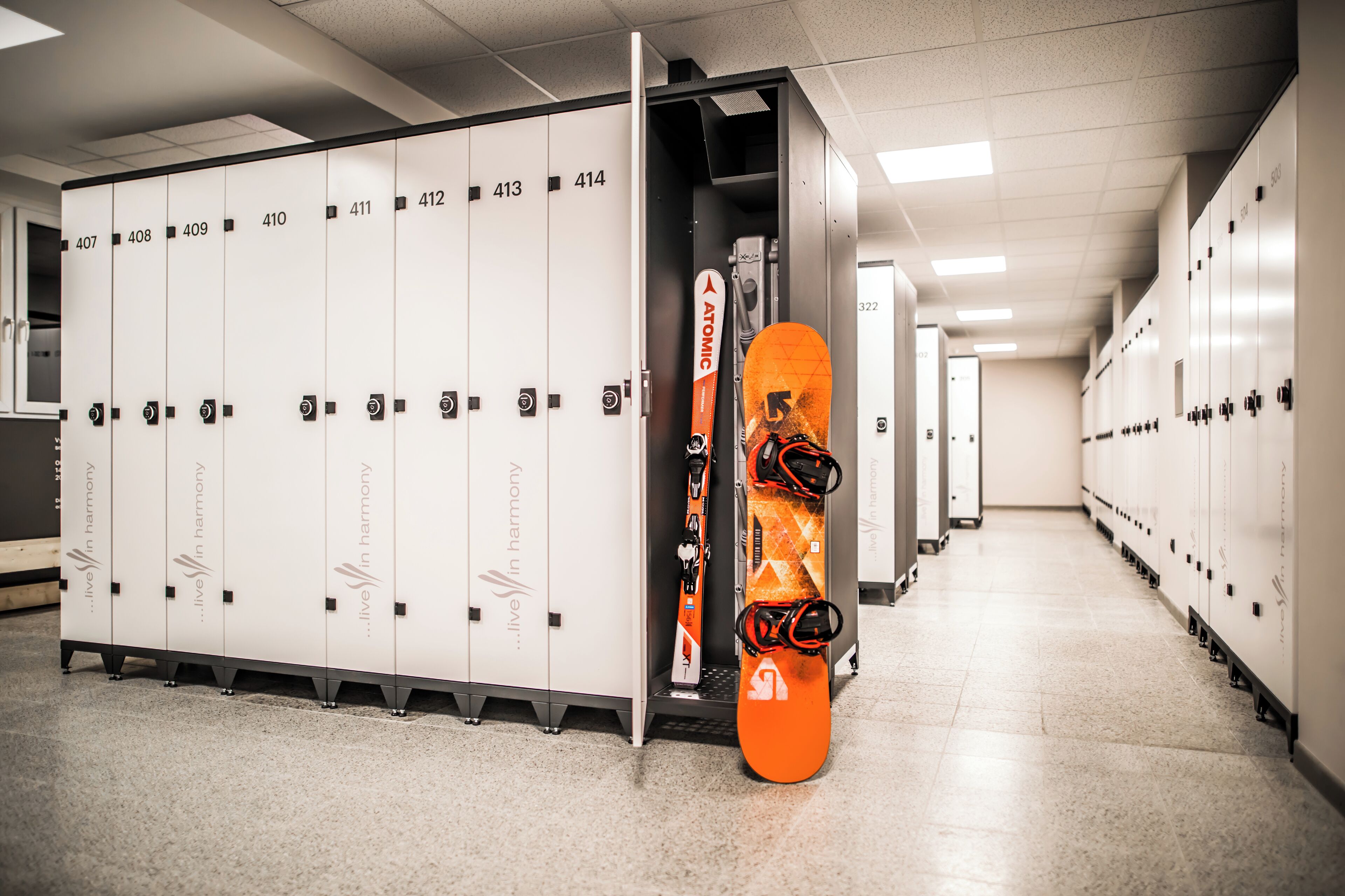 Un vestiaire avec des casiers numérotés et une planche de snowboard appuyée contre un mur.