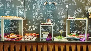 A buffet table with various dishes and a chalkboard wall with food-related drawings and text.