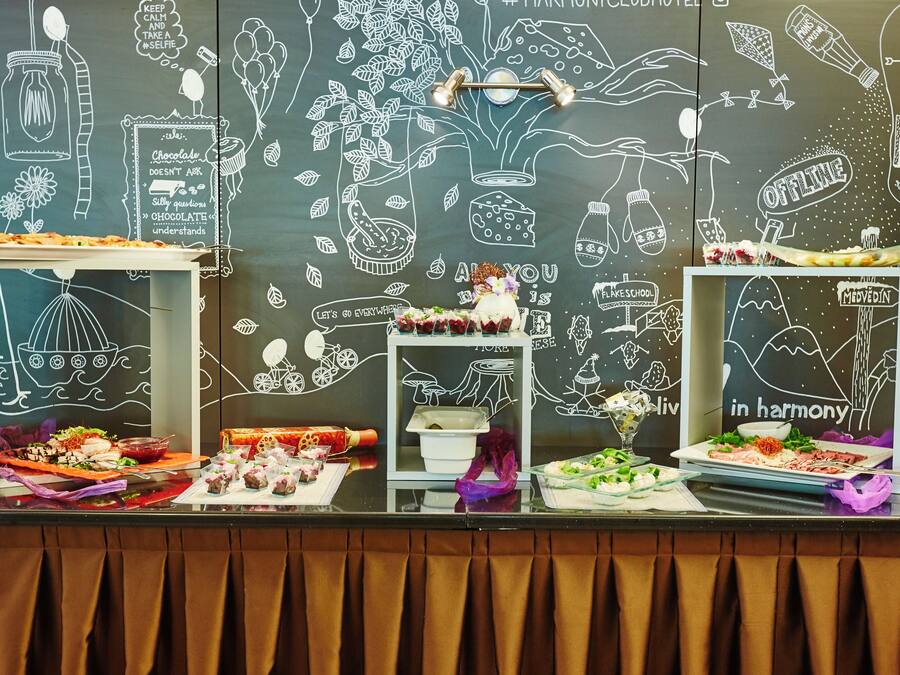A buffet table with various dishes and a chalkboard wall with food-related drawings and text.