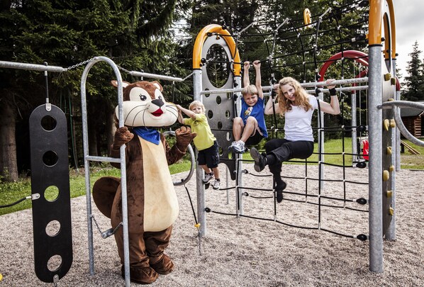 Un parque infantil con un personaje con temática de mono y diversas estructuras de juego.