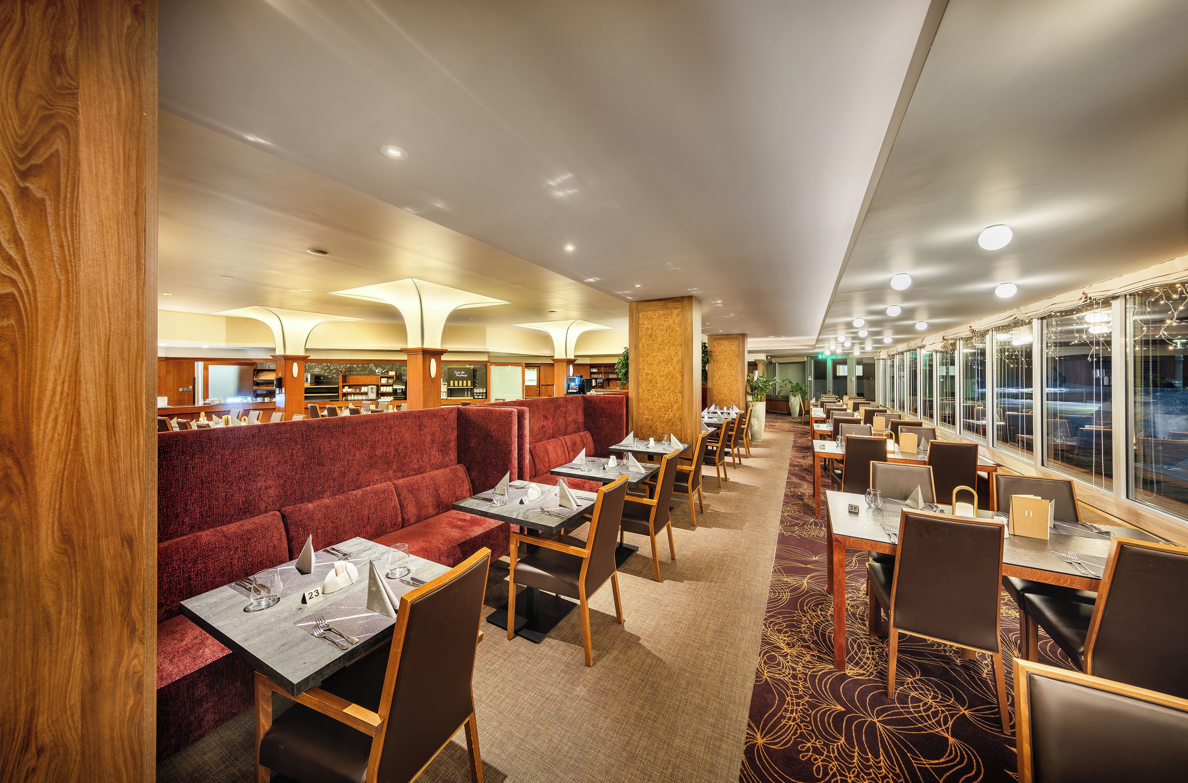A restaurant with booths and tables, wooden accents, and a carpeted floor.