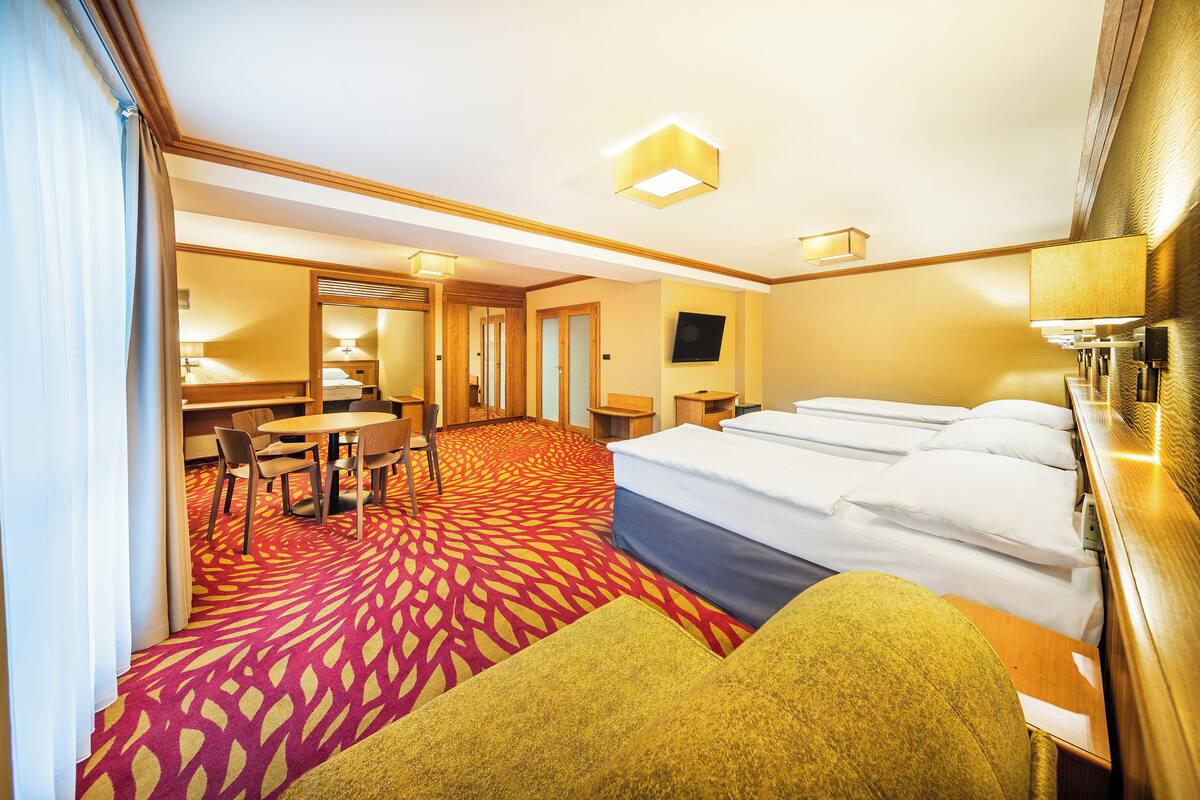 A hotel room with a large bed, a desk, a chair, and a TV.