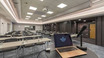 A conference room with tables, a laptop, and a microphone.