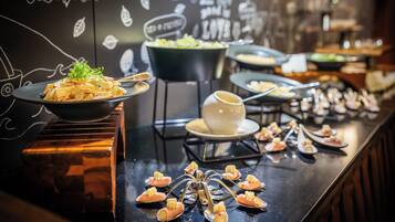 A buffet with various dishes and a decorative wall with white drawings.