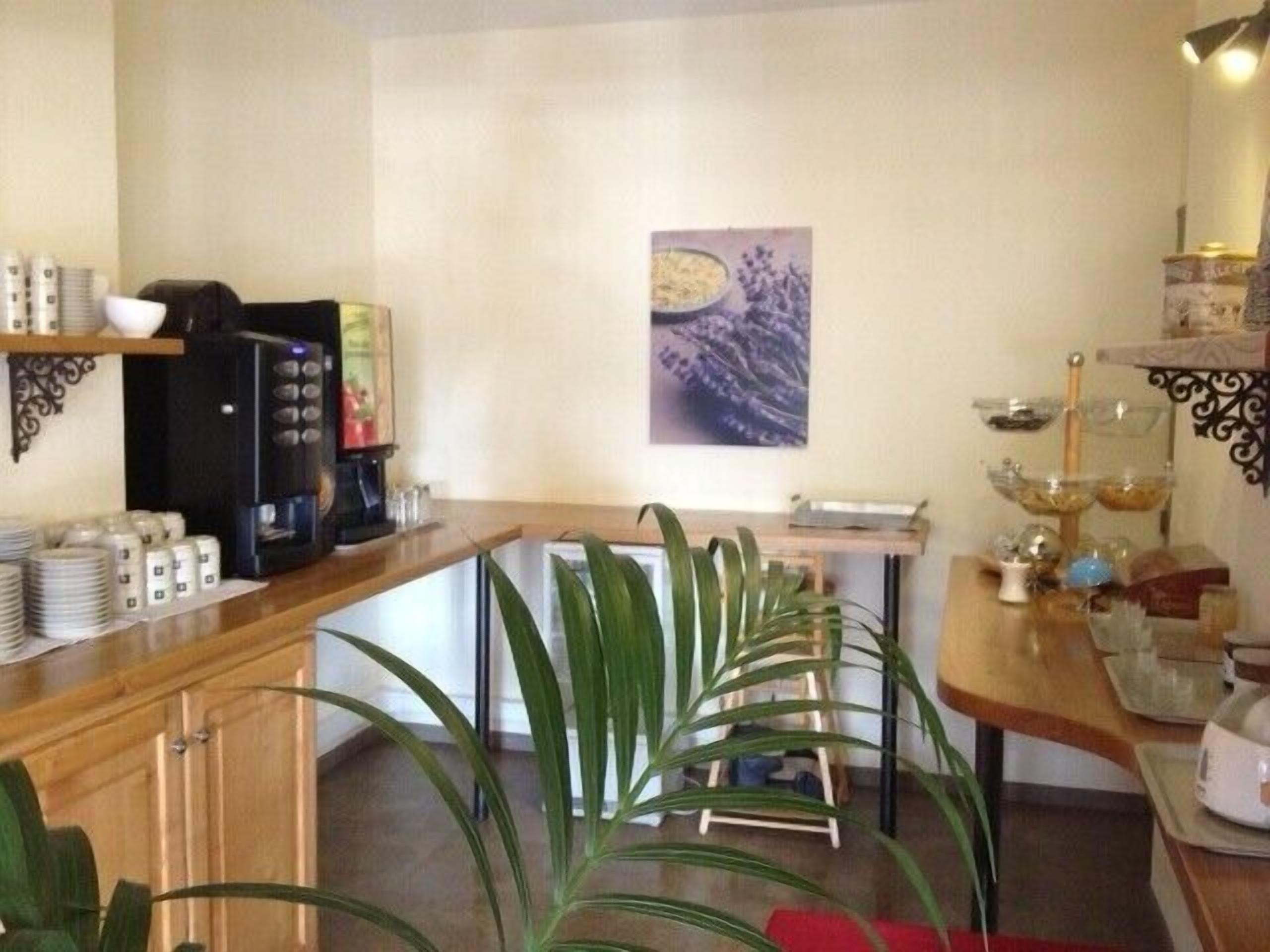 A kitchen with a coffee machine, a refrigerator, and a plant.