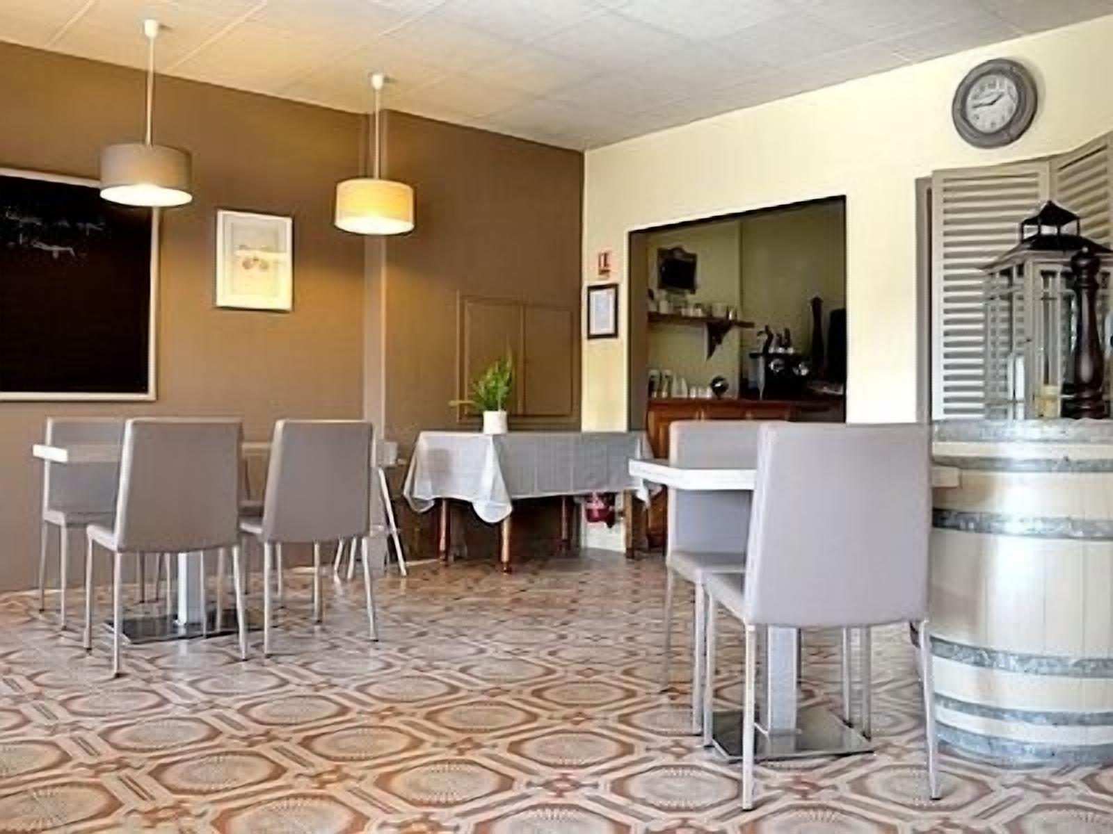 Un'area pranzo con pavimento decorato, un tavolo con sedie, lampade a sospensione e un orologio appeso al muro.