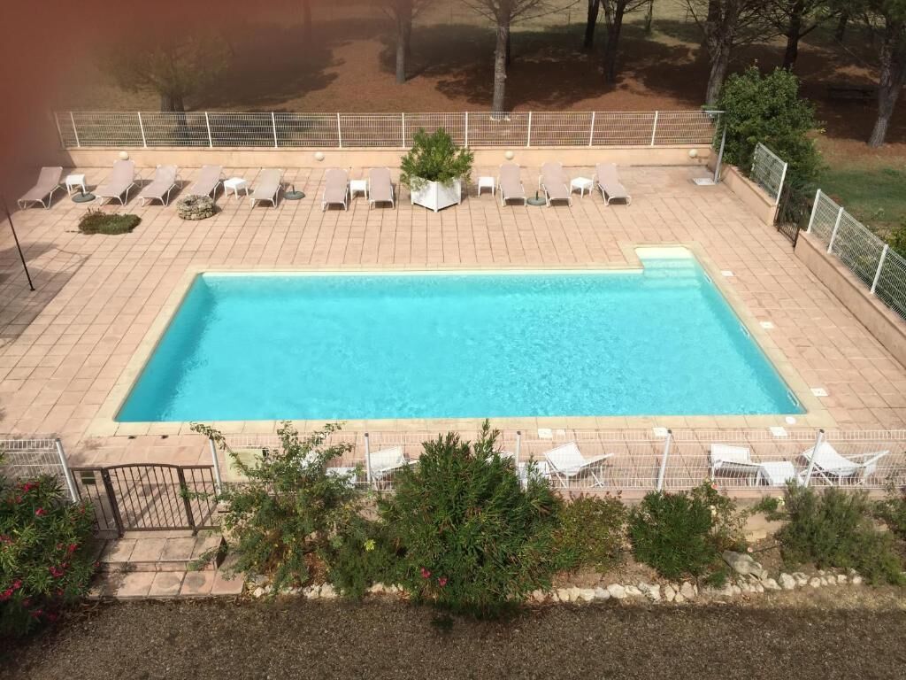 A rectangular swimming pool with lounge chairs and a small garden area.