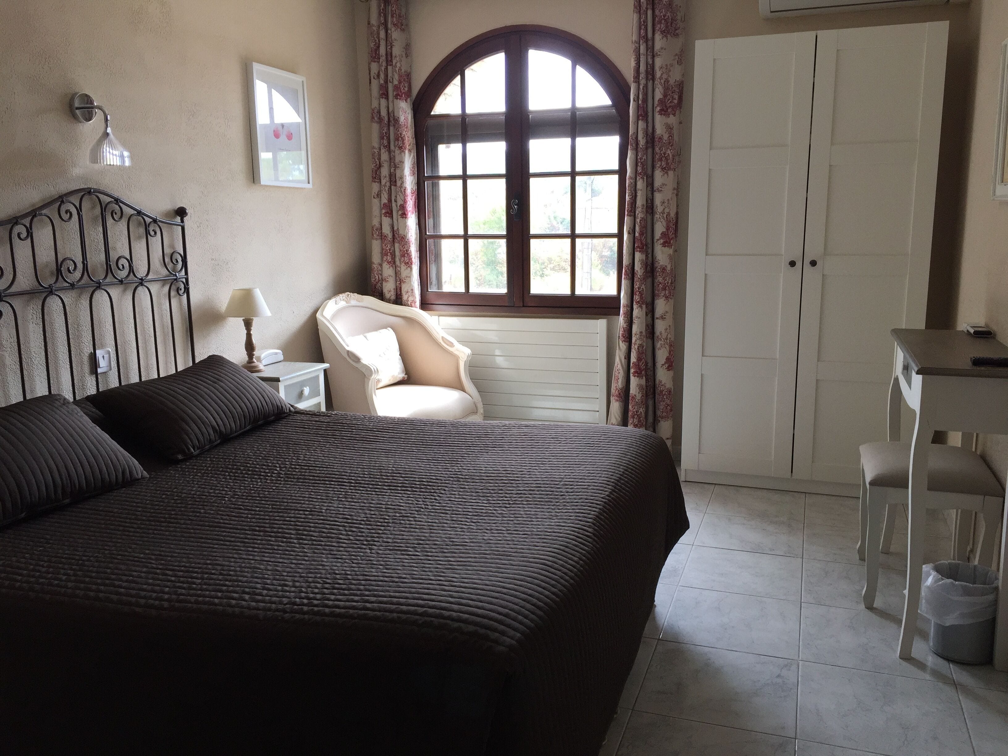 Een slaapkamer met een groot bed, een stoel, een bureau en een kledingkast.