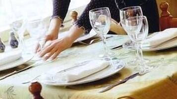 A dining table set with plates, glasses, and cutlery, covered with a tablecloth.