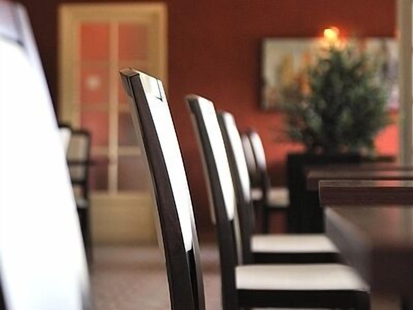 A row of black and white chairs with a wooden table in a dining area.