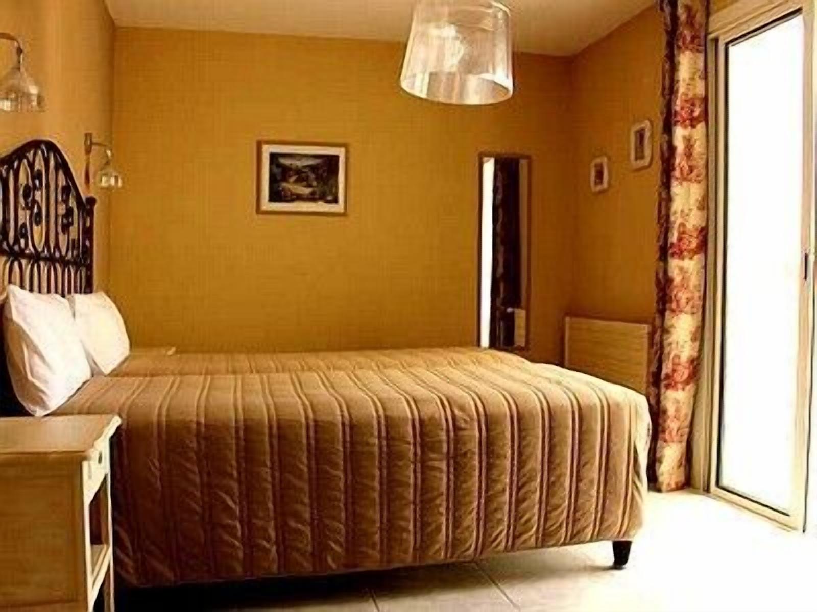 A bedroom with a bed, a nightstand, a lamp, and a door.