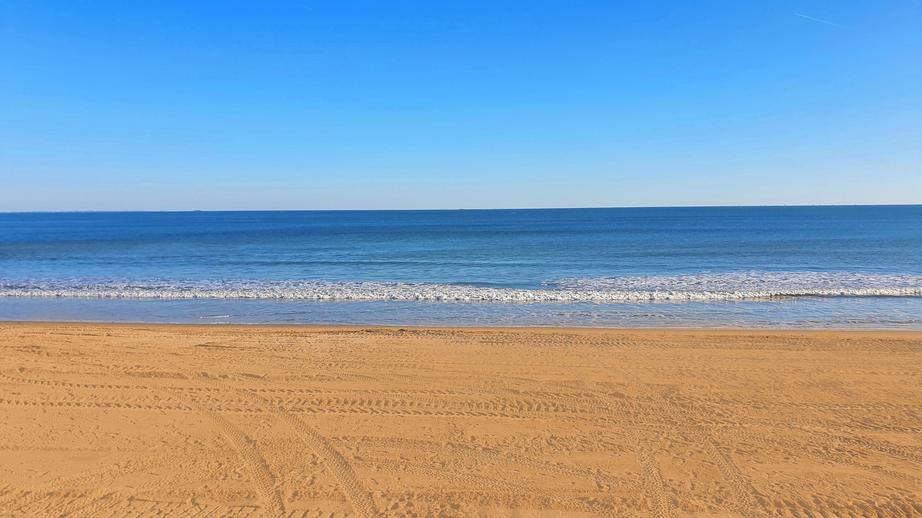 Une plage avec un ciel dégagé et une mer calme.