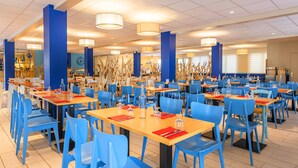 A spacious dining area with blue chairs and wooden tables, featuring a modern ceiling design and pendant lighting. - Azureva Pornichet - Baie de La Baule (Pornichet)