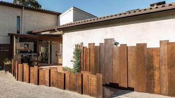 A modern building with a wooden fence, a gravel driveway, and a clear sky.