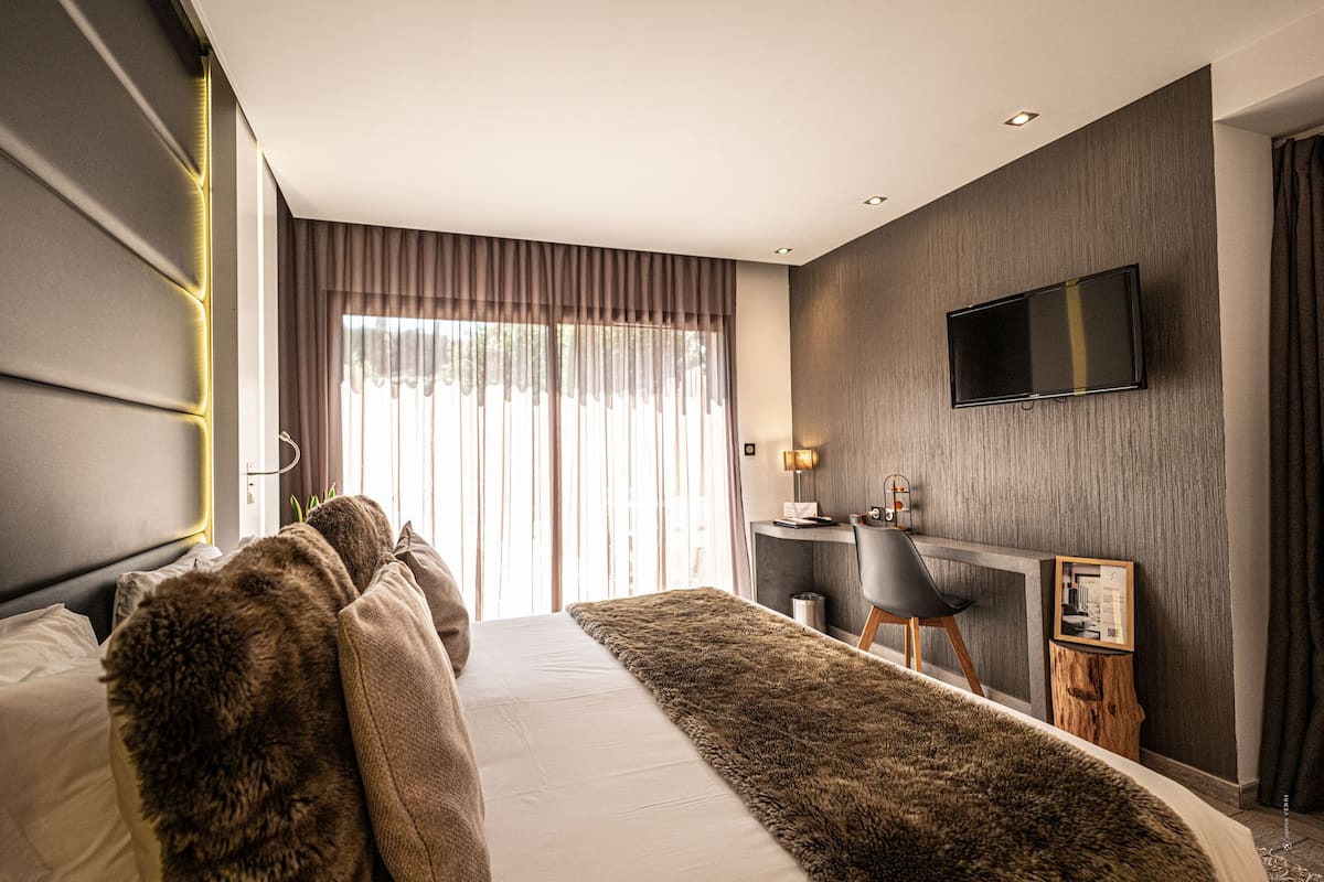 Una habitación de hotel moderna con una cama grande, un escritorio y un televisor de pantalla plana en la pared.