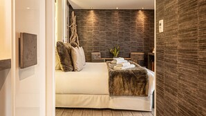 A modern bedroom with a large bed, a wooden floor, and a dark textured wall.