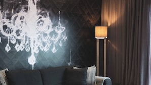 A modern living room with a dark geometric wall, a grey sofa, a coffee table, and a floor lamp.