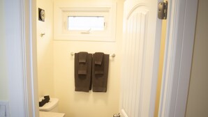 A narrow bathroom with a toilet, sink, and towel rack. - Stardust Motel (Camrose)