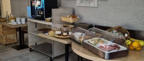 A modern kitchen with a coffee machine, a buffet table with food items, and artwork on the wall.