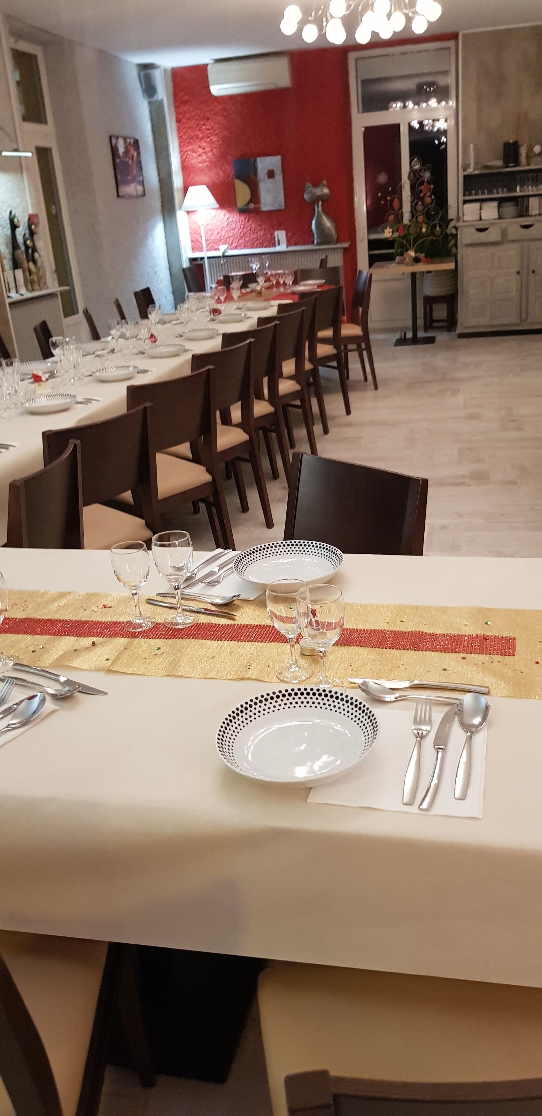 A dining area with tables set for a meal, chairs, and a kitchen in the background.