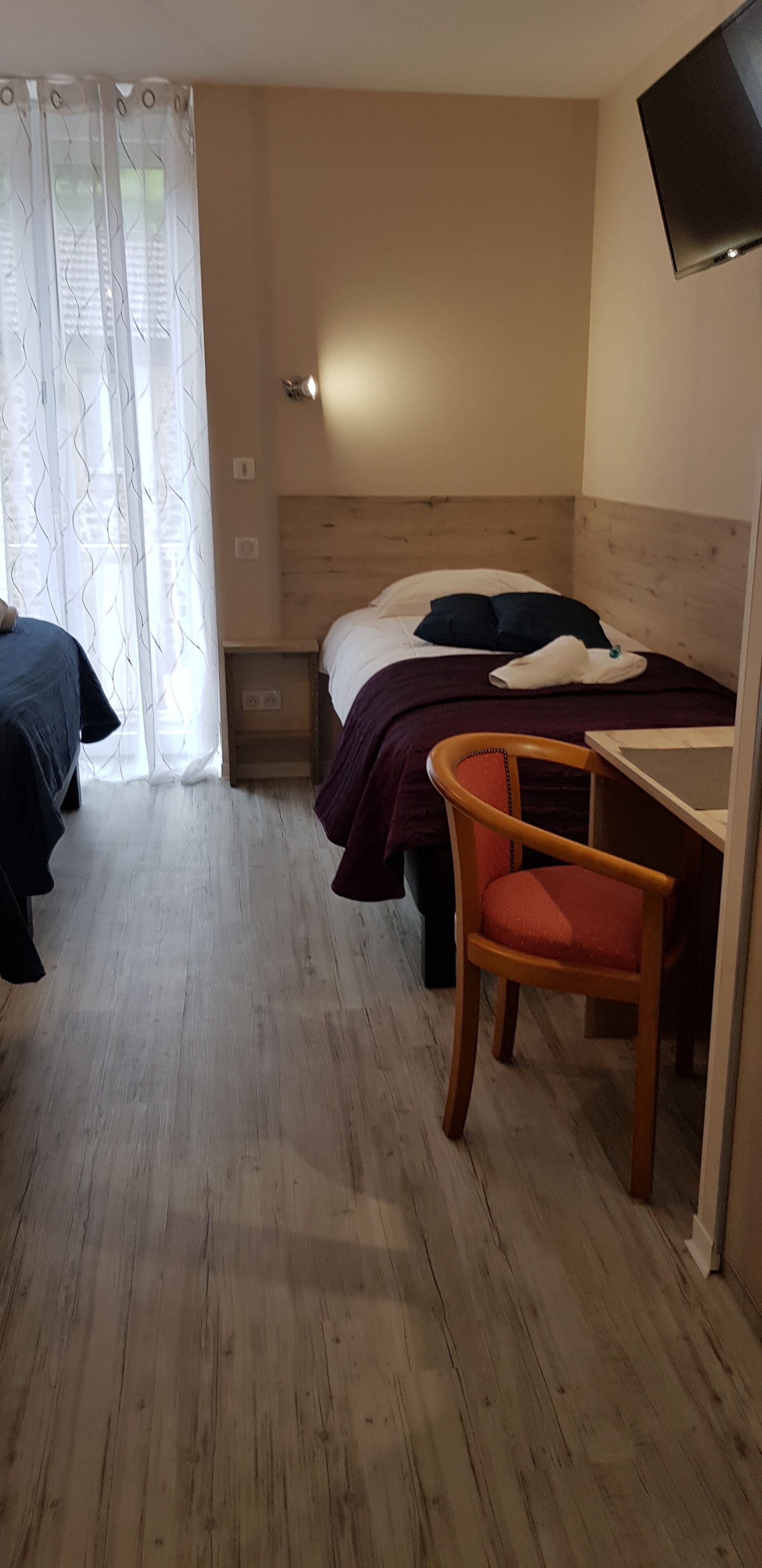 Una habitación de hotel con una cama, un escritorio, una silla y un televisor.
