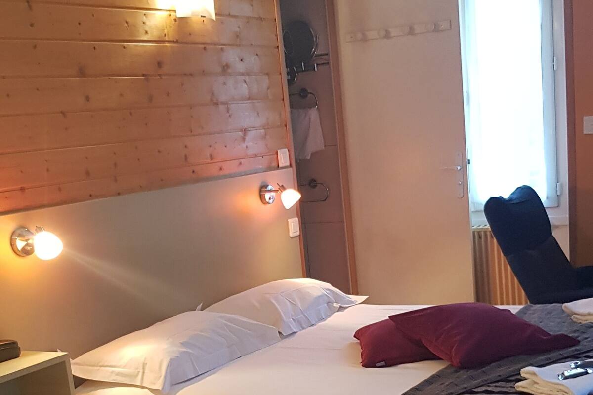 Une chambre d’hôtel avec deux lits, une tête de lit en bois et une fenêtre avec des rideaux.