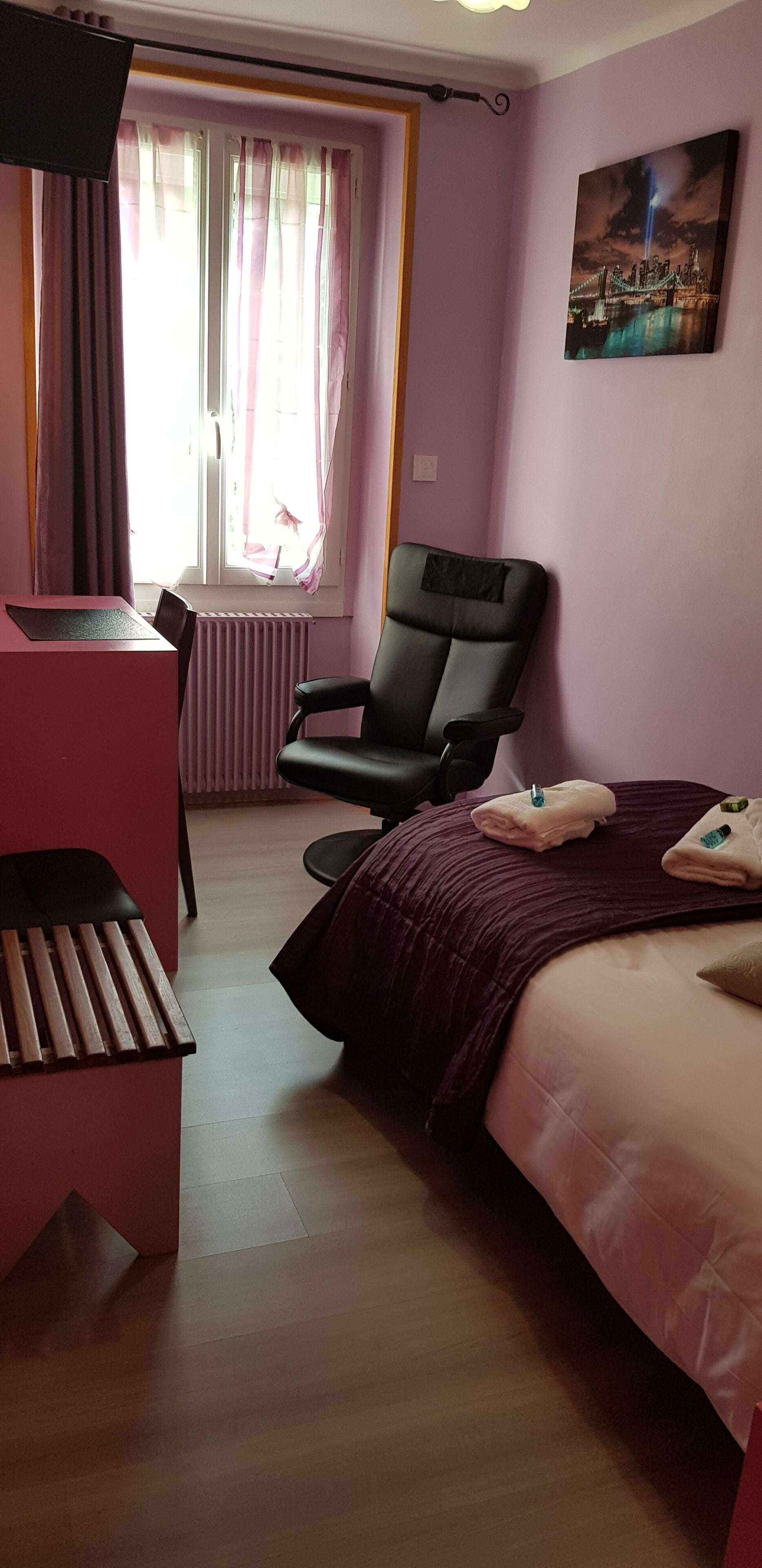 Une chambre d’hôtel avec un lit, un bureau, une chaise et une fenêtre avec des rideaux.