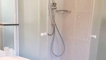 Une salle de bain moderne avec une douche à parois de verre, un lavabo blanc et un meuble bleu.