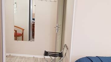 A bedroom with a bed, a chair, a mirror, and an air conditioning unit.