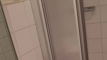 Une salle de bain avec un lavabo blanc, une cabine de douche en verre et un porte-serviettes.