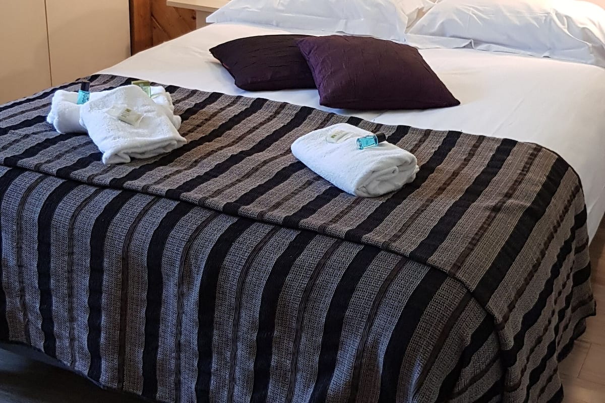 Un lit bien fait, avec une literie à rayures, une tête de lit en bois et une table de chevet avec une lampe.