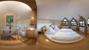Une chambre avec un grand lit, une salle de bain avec une baignoire et un escalier.